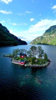 Huzurlu bir adada, canlı kırmızı bir kulübe Lovrafjorden Norveç 'in göz kamaştırıcı manzaralarını karşılıyor..