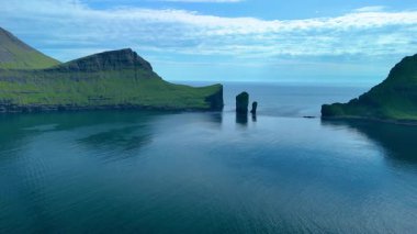 Faroe Adaları 'ndaki nefes kesici Drangarnir uçurumlarını keşfedin. Sakin turkuaz sulardan görkemli bir şekilde yükseliyorlar. Bu çarpıcı manzara, el değmemiş doğayı ve dingin güzelliği sergiliyor..