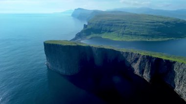 Faroe Adaları 'nın büyüleyici doğal güzelliklerini keşfedin. Huzurlu sulara inen görkemli uçurumlar, yemyeşil, Sorvagsvatn Gölü ve Vagar ile çevrili.