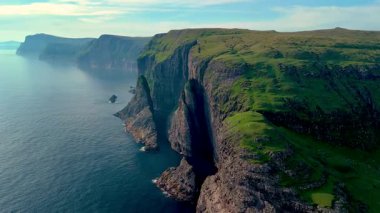 Zümrüt yeşili manzaraların derin mavi okyanusla buluştuğu Faroe Adaları 'nın nefes kesici uçurumlarını keşfedin. Çarpıcı kaya oluşumları izleyicileri cezbeden çarpıcı bir doğal zemin oluşturur..