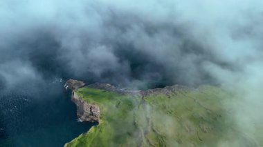 Faroe Adaları 'nın büyüleyici sahil kayalıklarını keşfedin. Gizemli bir sis tabakasıyla kaplanarak saf güzellikleri açığa çıkarın. Dramatik manzara sakin sularla buluşur. Macera ve merak uyandırır..