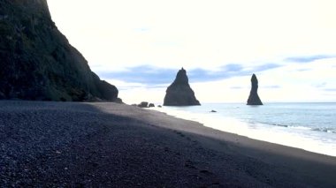 Eşsiz siyah kumları ve çarpıcı kaya oluşumlarıyla bilinen Reynisfjara Sahili İzlanda 'yı keşfedin. Sakin dalgalar ve dramatik uçurumlar sakin bir atmosfer yaratır. 