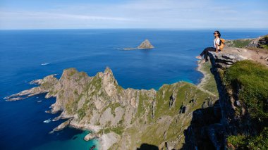 Matind Dağı 'nın kıyısında huzur içinde oturan bir insan Bleik plajının büyüleyici manzarasının ve Andoya' nın dramatik sahil şeridinin tadını çıkarıyor..