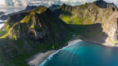 Ryten Kvalvika Sahili 'nin nefes kesici manzarası, yemyeşil dağların dingin bir gökyüzü altında durgun sularla buluştuğu yer. Macera arayanlar Norveç 'te doğanın güzelliklerini keşfediyorlar.