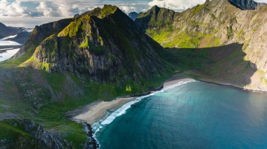 Kvalvika Sahili 'ni saran görkemli kayalıklar kıyıya doğru yavaşça dalgalanır. Güneş ışığı manzaraya dinamik gölgeler düşürür. Açık bir günde Lofotens 'ın büyüleyici doğal güzelliğini gösterir..