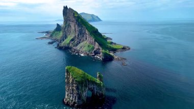 Zengin yeşilliğin derin mavi okyanusla buluştuğu Faroe Adaları 'ndaki nefes kesici Drangarnir uçurumlarını keşfedin. Bu çarpıcı manzara adaların eşsiz cazibesini ve engebeli güzelliğini özetliyor..