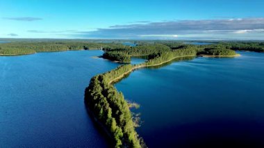Finlandiya, Punkaharju 'nun sakin cazibesini tecrübe edin. Çevrede parıldayan göllerle çevrili dolambaçlı bir doğa köprüsünü gösterin. Bu doğa harikası yemyeşil ve dingin sularıyla büyülüyor..