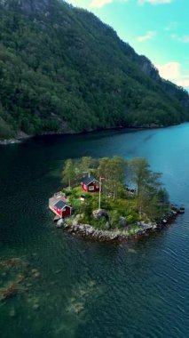 Norveç 'te yemyeşil ve sakin sularla çevrili büyüleyici kırmızı kulübelerin bulunduğu nefes kesici manzarayı keşfedin. Doğa aşıkları ve seyahat meraklıları için ideal..