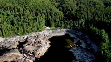 Yükselen ağaçların arasına yerleşmiş büyüleyici bir karavan Norveç 'in sakin sularına bakıyor. Norveç 'te İskandinav yabanı ve ormanda bir göl.