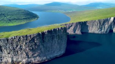 Derin mavi suların üzerinde dramatik uçurumların yükseldiği Faroe Adaları 'nın çarpıcı manzarasını keşfedin. Sorvagsvatn Gölü, Vagar