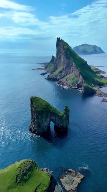 Faroe Adaları 'nın göz kamaştırıcı Drangarnir kaya oluşumlarını keşfedin. Parlak mavi gökyüzü altında sakin sular ve dramatik uçurumlar. Bu uzak cennetin dokunulmamış güzelliğini hisset..