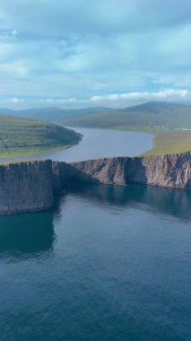 Feroe Adaları 'nın nefes kesici güzelliğini keşfedin. Sakin suların üzerinde görkemli bir şekilde yükselen sarp kayalıklar, yemyeşil manzaralar ve keşfedilmeye davet eden canlı bir gökyüzü..