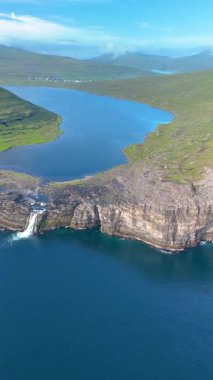 Faroe Adaları 'nın çarpıcı güzelliğini dramatik uçurumların ve çağlayan şelalelerin havadan görünüşüyle yaşayın. Durgun sular güneşin altında parlar, Sorvagsvatn Gölü, Vagar