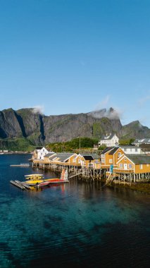 Norveç 'in göz kamaştırıcı Lofoten Adaları' na kurulmuş renkli bir balıkçı köyü olan Sakrisoy 'un cazibesini keşfedin. Parlak kamaralar görkemli dağlarla çevrili berrak suları yansıtıyor..