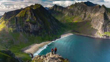 Maceracılar, Lofoten, Norveç 'teki çarpıcı Ryten Kvalvika Sahili Patikası üzerinde panoramik manzaranın keyfini çıkarıyorlar.