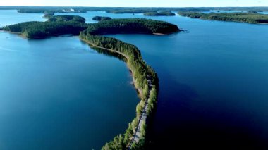 Bereketli yeşilliğin parlak gökyüzünün altında kristal berrak sularla buluştuğu Finlandiya, Punkaharju 'nun dolambaçlı yol oluşumuna hayret. Bu eşsiz manzaranın dingin güzelliğini hissedin..