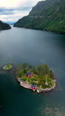 Norveç 'te yemyeşil ve sakin sularla çevrili huzurlu bir adada yuva yapmış büyüleyici kırmızı bir kulübeyi keşfedin. Rahatlamak ve macera yaşamak için mükemmel bir yer..