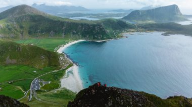 Lofoten, Norveç 'teki Haukland Sahili' ne bakan Mannen Dağı 'nın nefes kesici manzarası. Bereketli yeşil tepeler turkuaz sulara doğru iniyor, maceraperestleri büyüleyici kıyı şeridini keşfetmeye davet ediyor..
