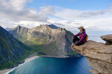 Solo yürüyüşçüler, Norveç 'in Lofoten kentindeki Ryten Kvalvika Sahil Yolu boyunca dramatik bir uçurum kenarından nefes kesici panoramik manzaralardan hoşlanırlar..
