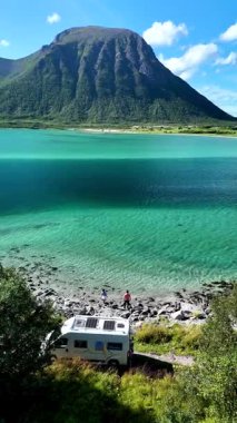 Göz kamaştırıcı bir Norveç kıyı şeridi boyunca uzanan bir erkek ve kadın sakin suların ve nefes kesici dağ zemininin tadını çıkarıyorlar. Norveç 'te kapalı bir yere park edilmiş bir karavanla yolculuk yapan bir çift.