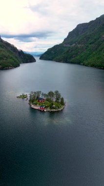 Norveç 'te gözlerden uzak bir adanın huzur veren cazibesini keşfedin. Görkemli dağlarla çevrili bu görkemli vaha canlı yeşillikleri ve kırsal kırmızı kulübeleri gözler önüne seriyor..