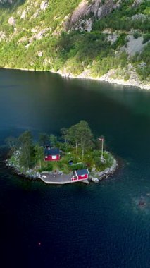 Norveç 'in dinginliğine yerleşmiş fiyortlara çarpan canlı kırmızı bir kulübe yeşil, yemyeşil bir adada manzarayı hazırlıyor..