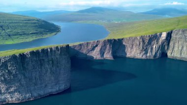 Faroe Adaları 'nın göz kamaştırıcı güzelliğini keşfedin. Uçsuz bucaksız yeşil uçurumlar, el değmemiş mavi suların üzerinde süzülüyor. Güneşli bir havada bu uzak cennetin sakinliğini hissedin..