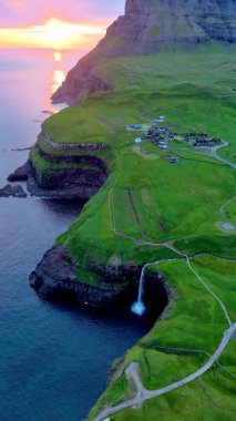 Gasadalur Şelalesi 'nin Atlantik Okyanusu' na dökülen ve Faroe Adaları 'nın gün batımında yemyeşil tepeler ve dramatik uçurumlarla çevrili nefes kesici güzelliğine tanık olun..