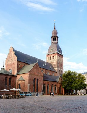 Riga, Letonya, 26 Ağustos 2025, Ziyaretçiler parlak mavi gökyüzüne karşı kurulmuş, Letonya 'nın en ikonik simgelerinden biri olan kırmızı tuğlalı katedrale hayran kaldılar.