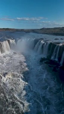 Su, Selfoss 'un kayalıkları üzerinde şiddetli bir şekilde yükseliyor ve çevresindeki manzarada sisli bir atmosfer yaratıyor. Selfoss şelalesi