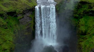 İzlanda 'daki nefes kesici Skogafoss şelalesine tanık olun. Suyun dingin bir havuza düştüğü yer. Etrafı canlı yeşillik ve sisle çevrili..