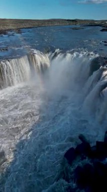 İzlanda 'nın engebeli manzaralarıyla çevrili kanyona dökülen selfoss şelalesinin ham gücüne tanık olun. Parlak güneş ışığı bu nefes kesici alanın doğal güzelliğini arttırır..