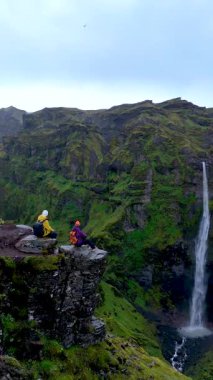İki kaşif İzlanda 'daki nefes kesen Mulagljufur Kanyonu' na bakan engebeli kayalıklarda oturuyor, yemyeşil ve çağlayan şelalelerle çevrili. Huzurlu bir an doğada güzellik.