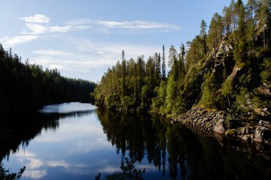 Kanyon Gölü Julma Olkky, Finlandiya 'nın Hossa Ulusal Parkı' ndaki yemyeşil yemyeşil suları yansıtan nefes kesici manzaralar sunmaktadır. Huzur ve macera arayan doğa aşıkları için mükemmel..