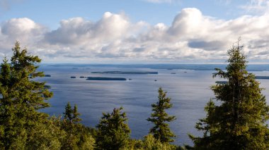 Pielinen Gölü 'nün engin mavi suları kabarık bulutlarla dolu bir gökyüzünün altında uzanır..