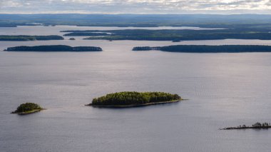 Bu çarpıcı manzara, Finlandiya 'daki Koli Milli Parkı' nın yeşil adalarla benekli ve uzak orman tepeleriyle çevrili sakin sularını içerir..