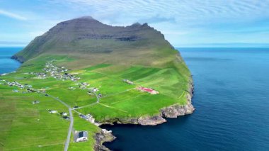 Faroe Adaları 'nın nefes kesici güzelliğini nefes kesici uçurumlar ve yeşil tepelerle tecrübe edin. Bu hava manzarası doğanın ve sahil boyunca geleneksel yerleşimlerin uyumlu bir karışımını sergiliyor..