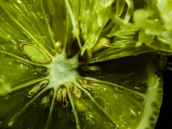 A green lemon is cut in the middle and the seed and lemon juice in the lemon shape nicely.