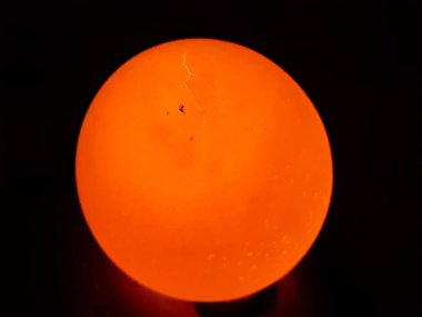 Bir yumurtanın arkasındaki ışık yanıyor ve yumurtanın parlak, siyah bir arka planı var. Bu, gecenin karanlığının bir resmi..