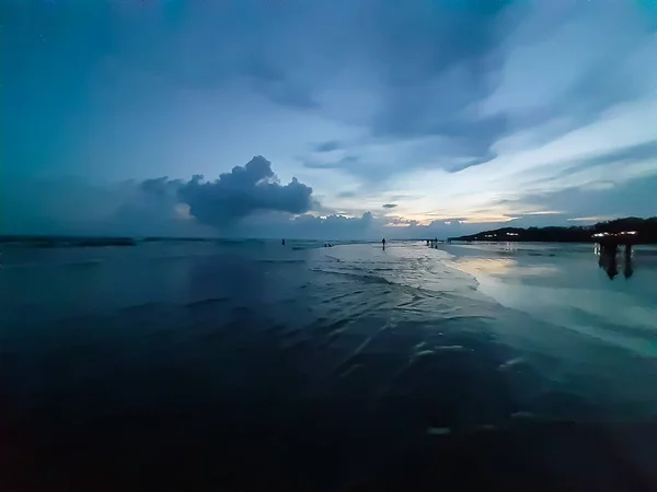 The beauty of India\'s long sea at sunset. Black clouds in the blue sky and the reflection of red sunlight.