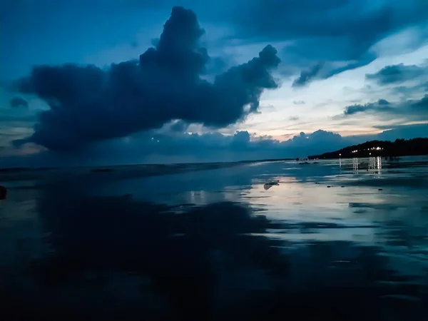 The beauty of India's long sea at sunset. Black clouds in the blue sky and the reflection of red sunlight.