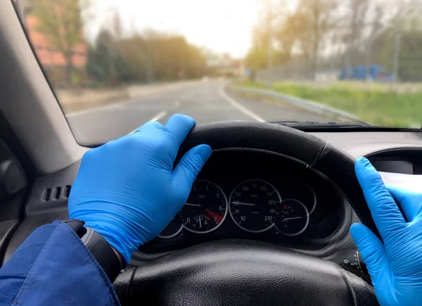The man drives a car, wears medical gloves, protects himself from bacteria and viruses, holds the steering wheel of the car. Protection against the coronation virus. Transport concept, quarantine and coronavirus disease.