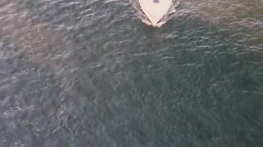 Çerçeveden tek bir kişinin geçtiği durgun su ve yatın havadan görüntüsü