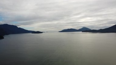 Gri bulutlar uzak dağlarla nehirde yansıyor.