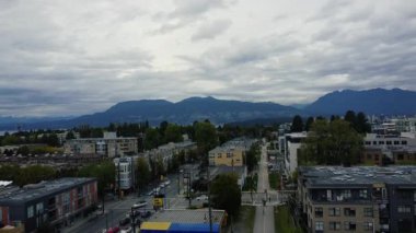 Yağmurlu bir günde Vancouver dağlarının ve şehir merkezinin açılış sahnesi.