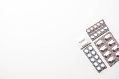 Beyaz masadaki paketlerde farklı ilaç hapları.