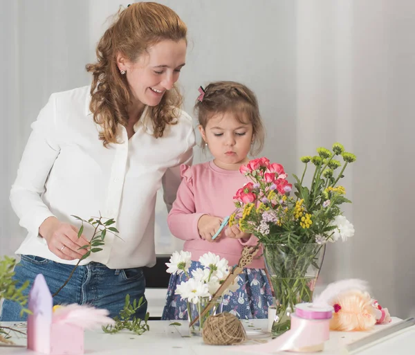 Mutlu anne ve kız tatil için buket yapıyorlar. Çiçeklerin aile işi. Anne ve kızı. Çiçekçi 