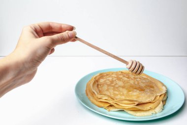 Lezzetli krepler mavi tabakta yatıyor. Ahşap zemin üzerine bal dökülmüş krepler. Metnin altına yerleştir. Stok fotoğrafı.