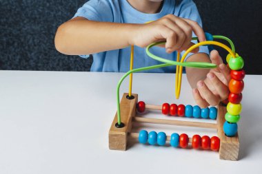 Çocuk Montessori oyunu oynuyor. Çocuk tahta oyuncak ayırıcı topluyor. Çok renkli geometrik şekiller, daire, kare, üçgen, dikdörtgen.