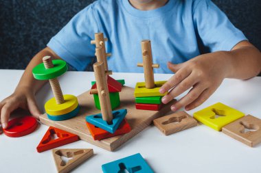Çocuk oyuncakları rengine ve şekline göre topluyor. Ahşap eğitici Montessori oyuncakları. Çocukların elleri yakın plan..
